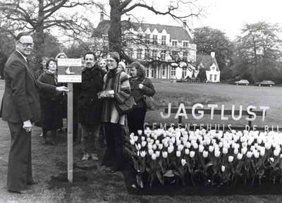 92326 Afbeelding van een groepje personen bij het plaatsen van een bordje bij de geplante vredestulpen op het gazon van ...
